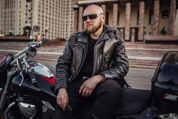 Fototapeta na wymiar Brutal man on a cool motorcycle against beautiful stately building