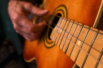 Old hands on a guitar. Grandfather plays the guitar. Old man plays the guitar.