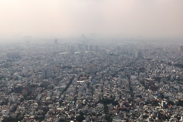 Obraz premium Dense air pollution and smog over Saigon, Vietnam (Ho chi Minh City). Overpopulated city, urban sprawl. Aerial view