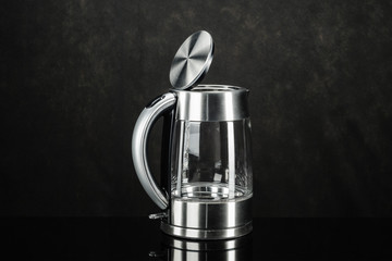 Glass stainless steel kettle on the black mirror background