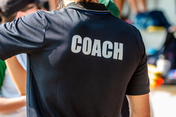 Back view of a male coach in black COACH shirt - obrazy, fototapety, plakaty