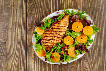 Salad with grilled turkey and vegetables on wooden table.