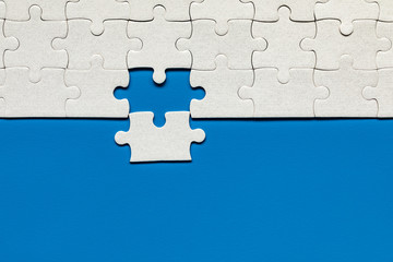 White jigsaw puzzle. White puzzle pieces on color background. Unfinished white jigsaw puzzle pieces...