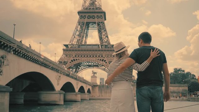 Happy traveler tourist couple of lovers near the Eiffel Tower in Paris under sunlight and blue sky. Famous popular touristic place in the world.