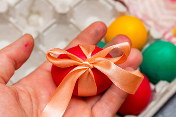 red egg with bow in hands for the Easter