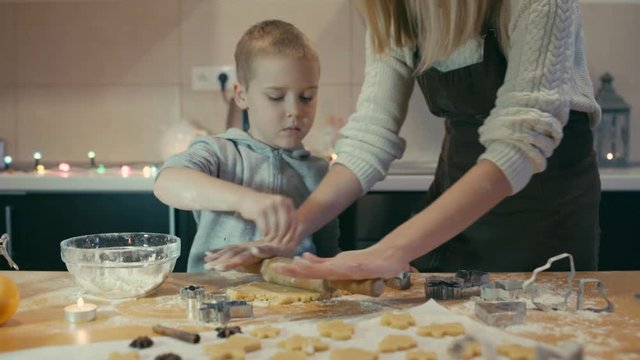 Mother and son baking Christmas cookies in the kitchen. Family life before the holidays at home.