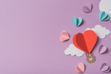 top view of colorful paper hearts and clouds around heart shaped paper air balloon on violet background