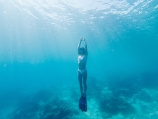 Young tourist using swimming equipment for ocean snorkeling near tropical coral reef, woman in flippers exploring underwater depth and aquatic life during wanderlust recreation vacations on Raja Ampat © BullRun
