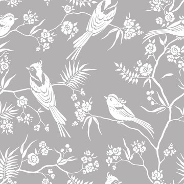 Seamless pattern in oriental style with blooming branches trees and birds. Wildlife silhouette, white floral ornament on gray background. Vector hand drawn illustration, garden in japanese style.