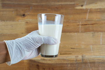 Using Medical latex against wooden background  and holding cup of milk 