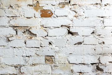 Crumbling from old age brick wall painted white