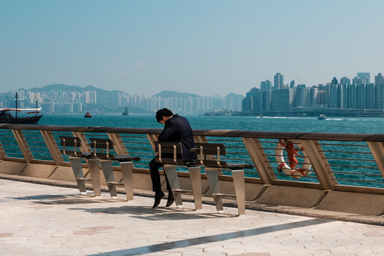 Man Looking At Mobile Phone Outdoors With Skyline Background, Hong Kong