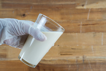 Using Medical latex against wooden background  and holding cup of milk 