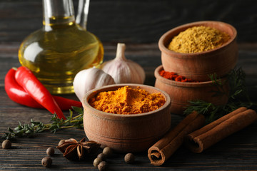 Bowls with spices and ingredients on wooden background, close up