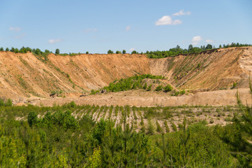 Landscape: inactive abandoned overgrown sand quarry under a blue sky