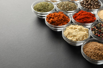 Bowls with different spices on black background, space for text