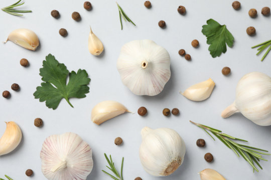 Flat lay of composition, garlic bulbs, slices, spice, parsley, rosemary on grey background, top view. Closeup
