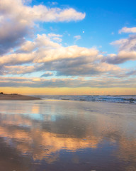 Beautiful warm golden sunlit clouds during sunset perfectly reflecting in the sand on a beach. Fire Island National Seashore - New York