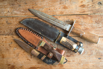 Various hunting knives on old wooden background flat lay
