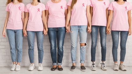 Unrecognizable Women In Pink T-Shirts Holding Hands Standing Near Wall