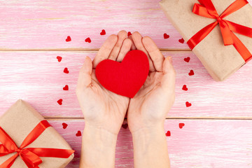 Woman Hands Holding Red Heart on Pink Wooden Background with Red Confetti Hearts. Concept of Health care, Love, Donation, Family Insurance, Happy Valentines Day. Top View