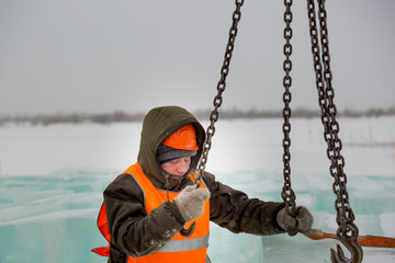 Slinger in orange helmet on shipment of ice blocks