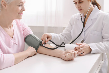 Fototapeta premium Doctor measuring arterial blood pressure for senior patient