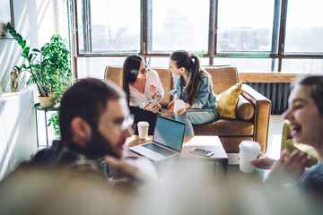 Young cheerful women smiling while catching up news at cozy living room