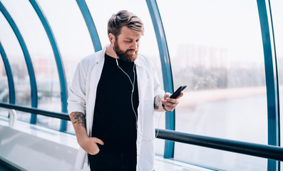 Man 30s checking received email from colleague while standing indoors and listening new music using...