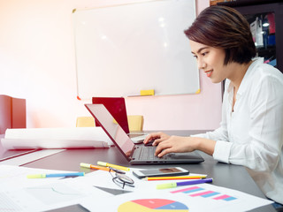 Beautiful happy Asian woman working with laptop computer on table in meeting room.