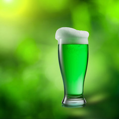 Glass of green beer on a blurred natural background.