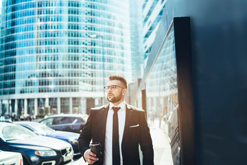 Smart male entrepreneur in formal suit drinking coffee at downtown