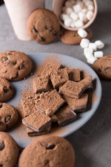 Cookies laid out on a table and a plate of marshmallows spilled out of a cup