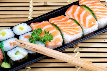 Take-out style plastic plate with Japanese maki and salmon sushi.