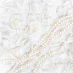 Obraz na płótnie Canvas Pearl necklace on a background of white rose petals. Ideal for greeting cards for wedding, birthday, Valentine's Day, Mother's Day