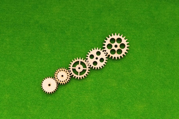 A group of wooden gears on a green background. Mechanism, interaction, connection.