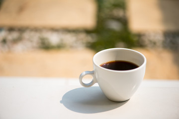 A white cup and black coffee on table
