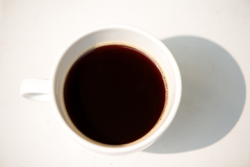 A white cup and black coffee on table