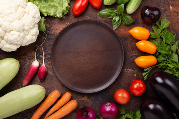 Brawn wood plate and fresh farmers garden vegetables on wooden table. Harvest time. Top view