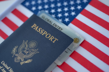 Global Entry card (Trusted traveller) covered of Passport of United states of America on American flag surface. Diagonal Close up view.