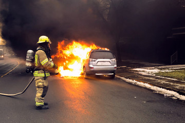 Firefighter extinguish a car fire with fire hose