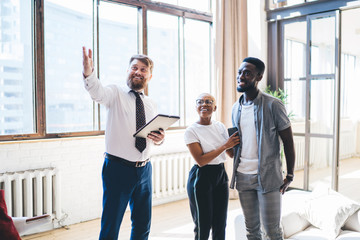 Professional estate agent showing house to African American pleased couple