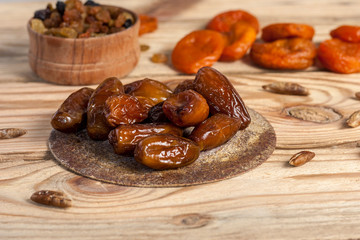 Tasty dates on a round substrate close-up on a wooden background