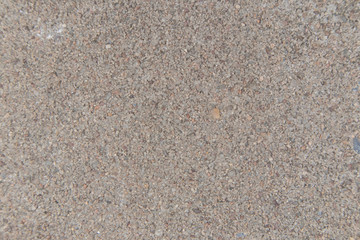 The surface of the concrete road has small grains of sand and black stains.