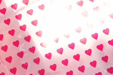 Pattern made of hearts on pink background with sun glare. Abstract love, St. Valentine's day backdrop. Top view, soft focus.