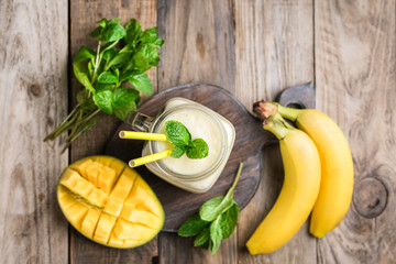 Delicious mango smoothie in mason jar on a rustic background. Healthy food, detox diet. Copy space..