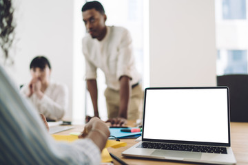 Office employees talking near laptop with empty screen