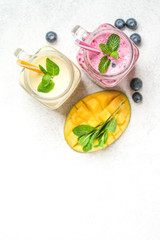 Delicious blueberry and mango smoothie in mason jar on a light background. Healthy food, detox diet. Copy space.