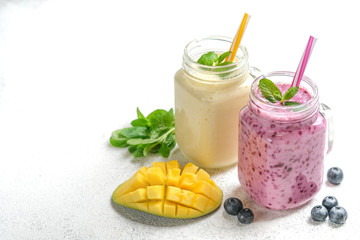 Delicious blueberry and mango smoothie in mason jar on a light background. Healthy food, detox diet. Copy space.
