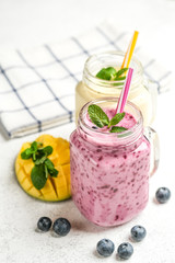 Delicious blueberry and mango smoothie in mason jar on a light background. Healthy food, detox diet. Copy space.